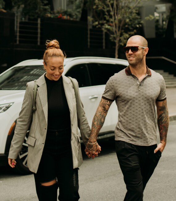 Chloe Dumont and Dany Simard holding hands while walking away from the INFINITI QX60