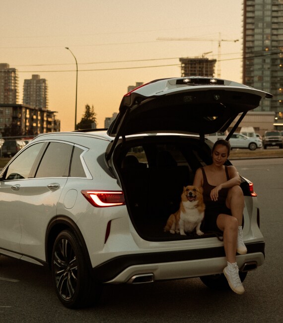 Miri Masso sitting in the INFINITI QX50 cargo space with her dog