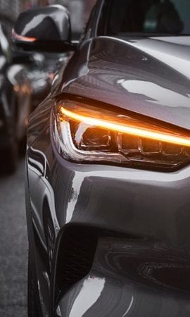 Mobile 428 x 926 wallpaper image of a QX50 Luxury Crossover's front headlight from straight on.