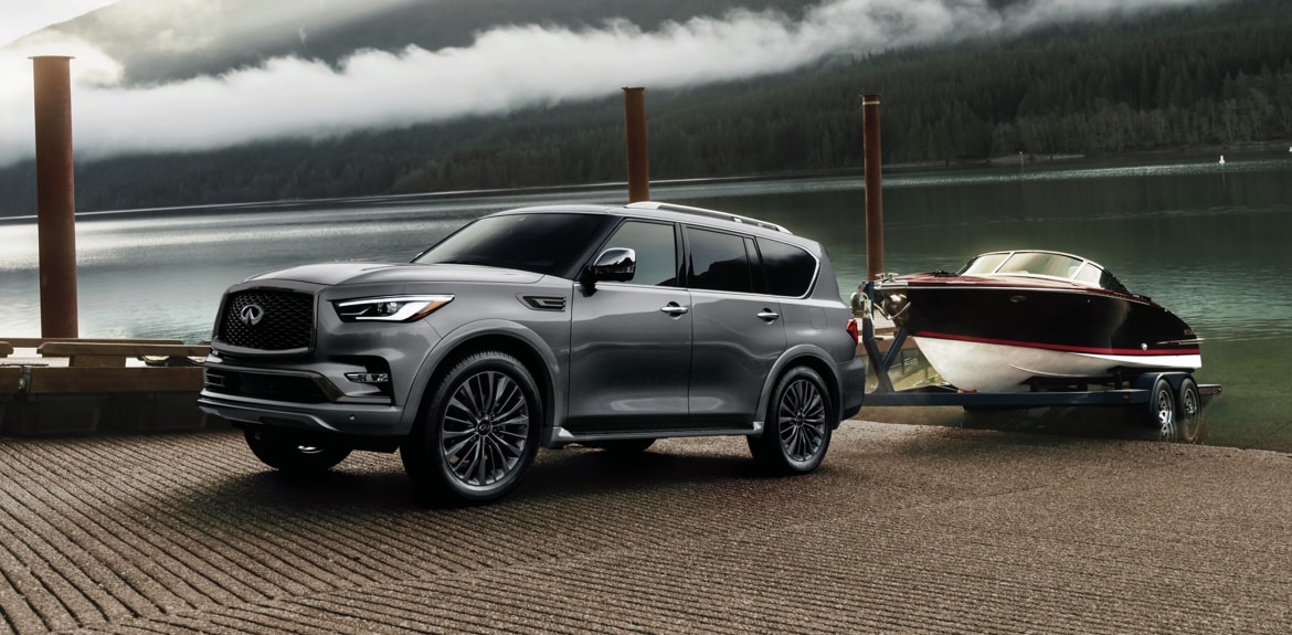 Desktop 1920 x 1080 wallpaper image of a grey QX80 full-Size Luxury SUV towing a boat out of water.