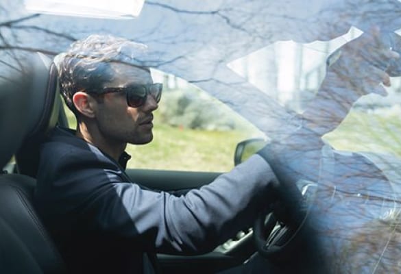 A man wearing sunglasses driving his INFINITI