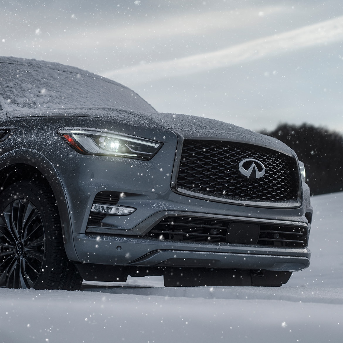 Front grille on an INFINITI SUV in snow showing off the logo badge
