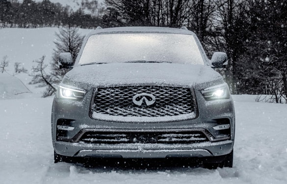A gray INFINITI luxury SUV driving in snow