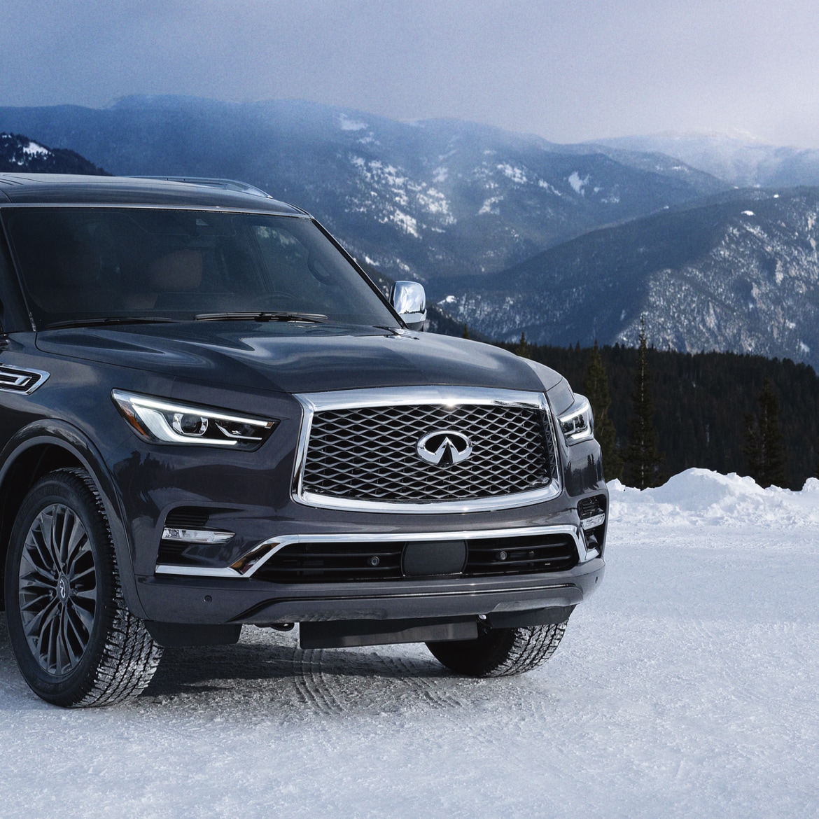 An INFINITI QX80 SUV parked on a snowy mountain