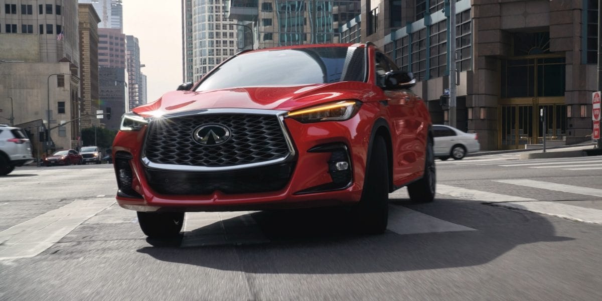 Front view of red INFINITI QX55 making a turn in a city road