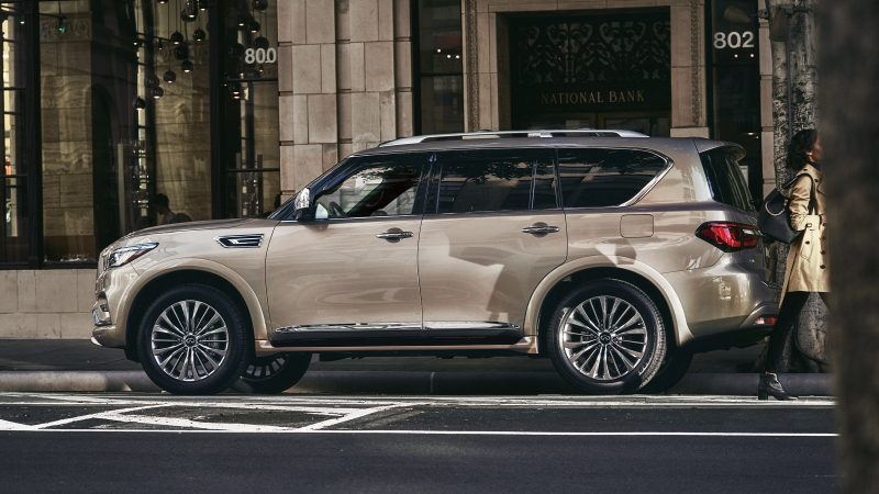 A side view of an INFINITI QX80 luxury SUV parked in a city
