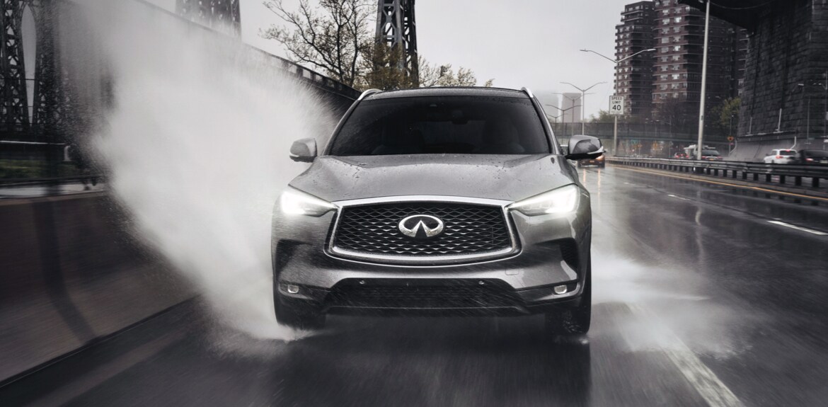 Front view of a 2022 INFINITI QX50 crossover driving fast on the road displaying its powerful Intelligent All-Wheel Drive system