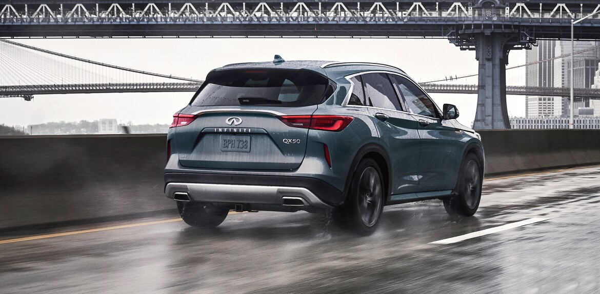 2023 INFINITI QX50 driving fast on wet highway, displaying intelligent all-wheel drive