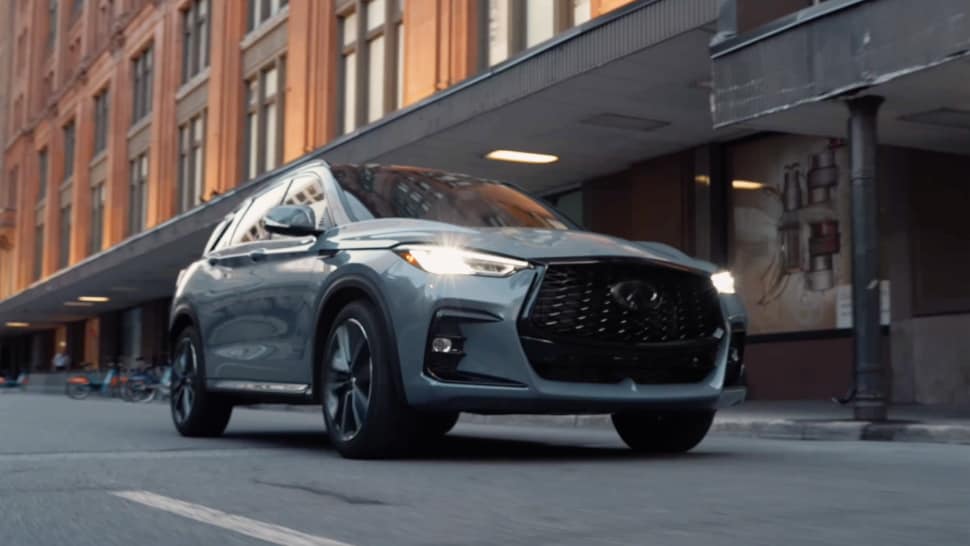 Front view of 2024 INFINITI QX50 driving through a city street
