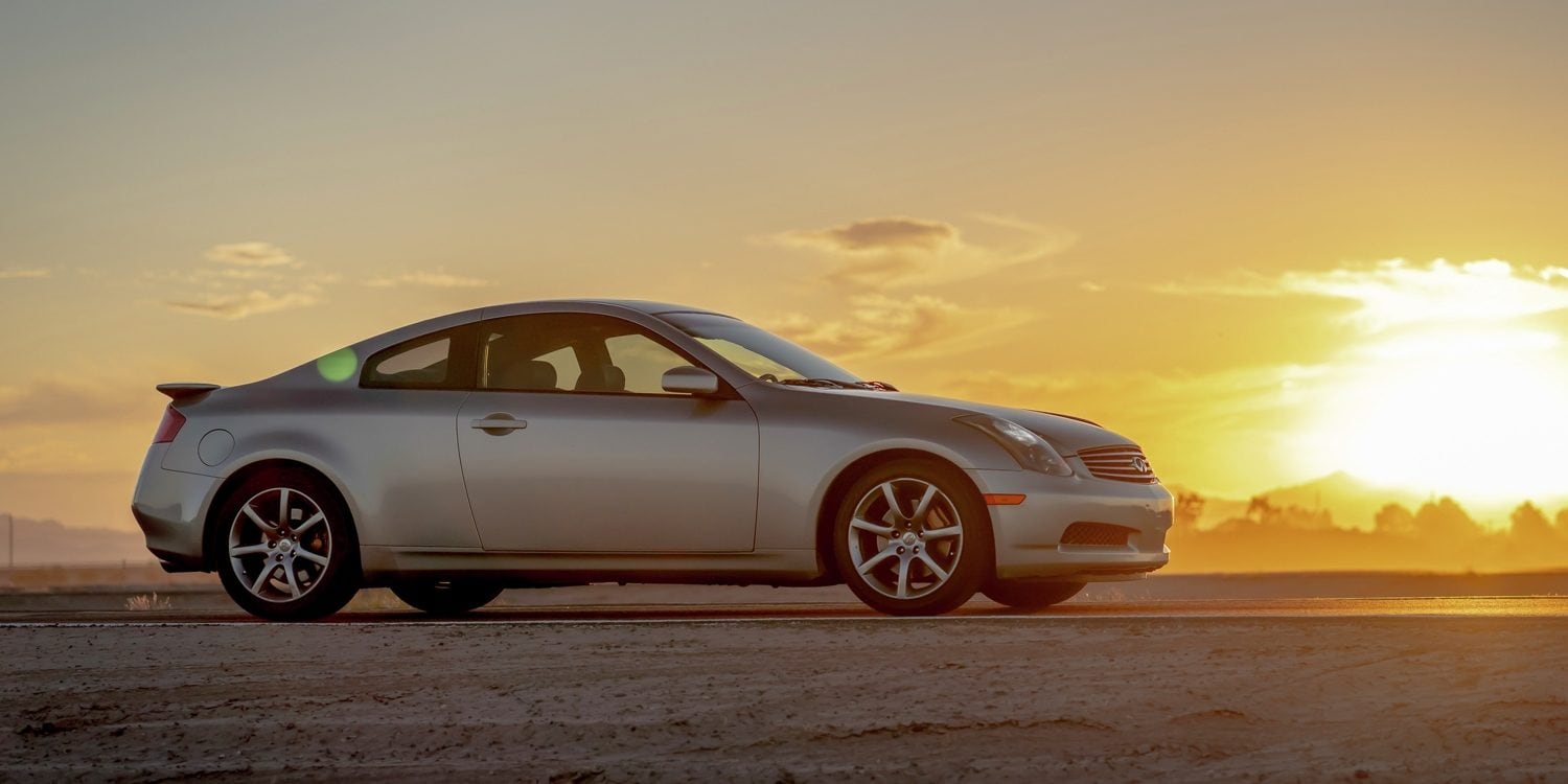 A silver INFINITI G35 parked with a sunset behind it.