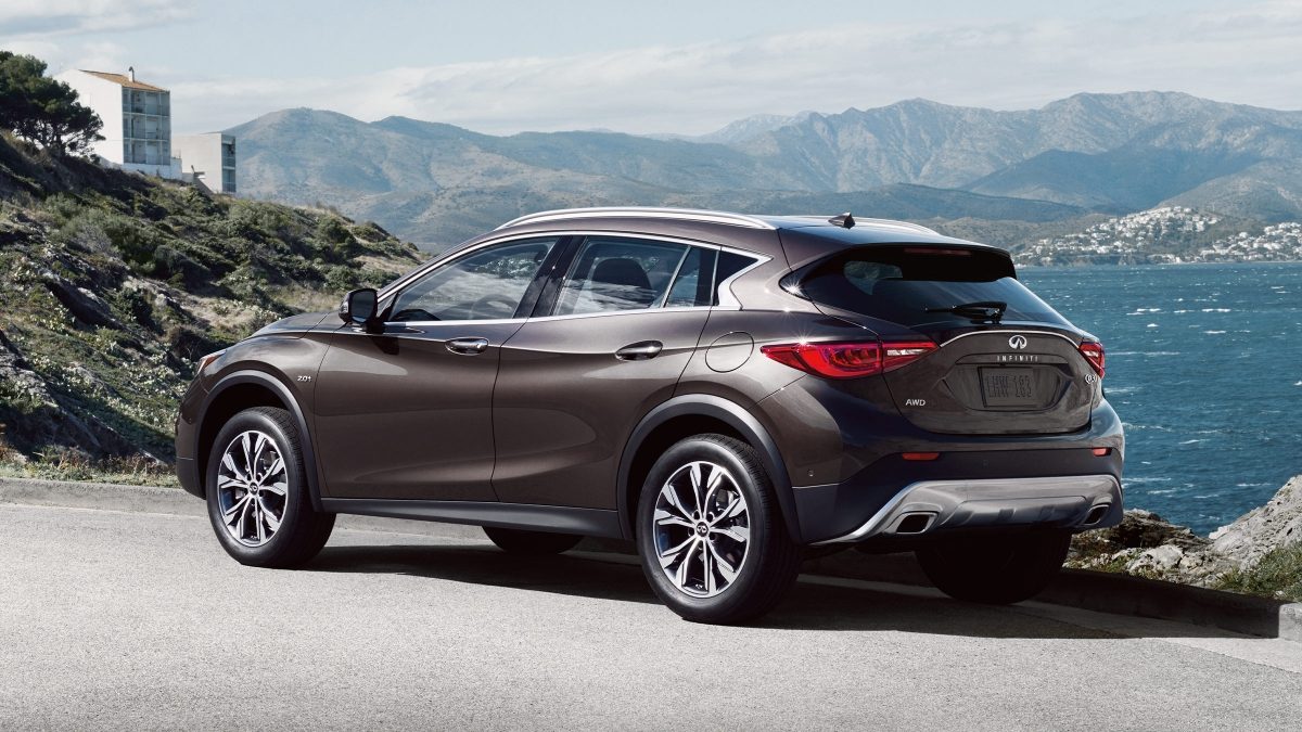 Rear view of an INFINITI QX30 luxury crossover parked with an ocean and mountains in the background