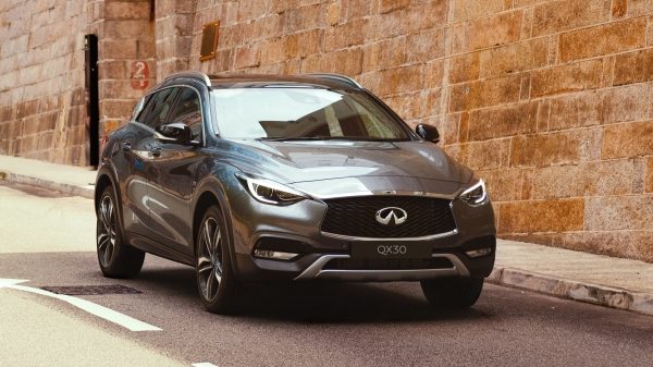 An INFINITI QX30 crossover parked near a stone wall