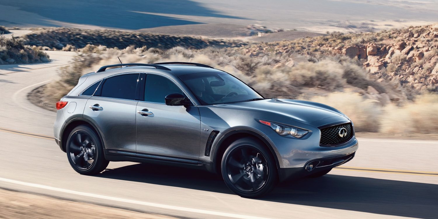 A side view of a gray INFINITI QX70 driving on a desert highway