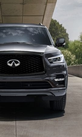 Mobile 428 x 926 wallpaper image of a grey QX80 Full-Size Luxury SUV's front grill and headlight.