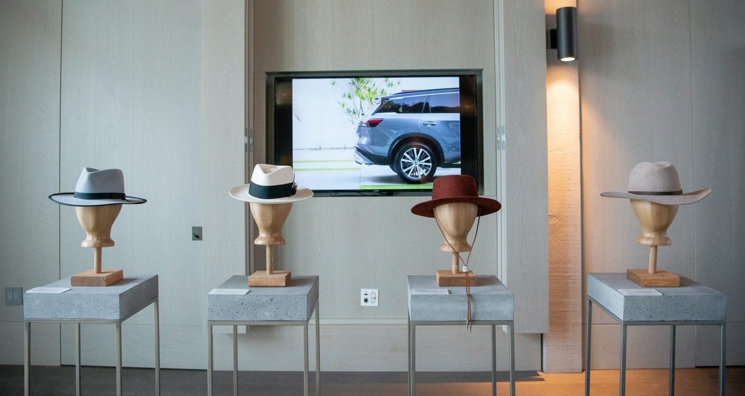Stylish hats on mannequin heads with a TV screen displaying the stylish 2022 INFINITI QX60 SUV